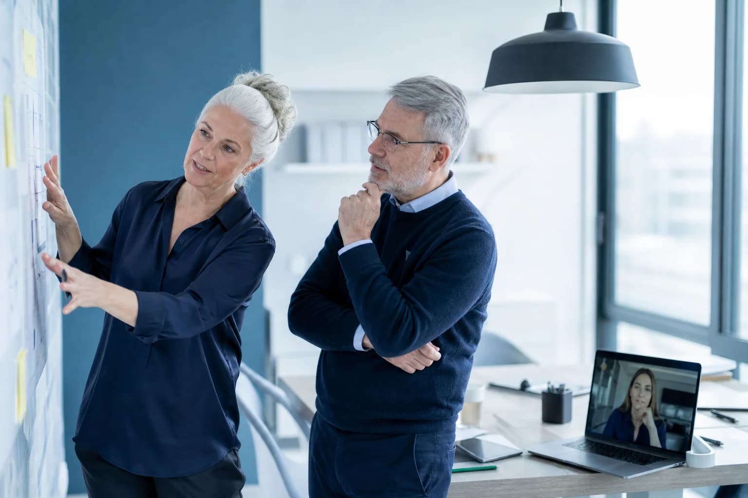 Engineering leaders planning with a remote developer in a modern office